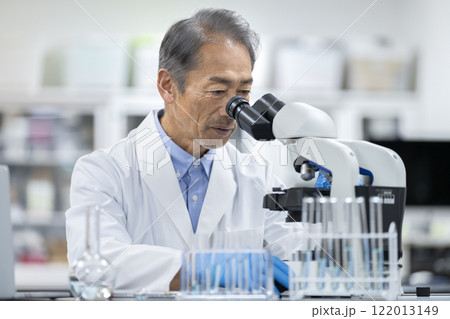 顕微鏡で作業をする白衣を着たシニア男性 実験・研究・開発イメージ 顕微鏡で作業をする白衣を着たシニア男性 実験・研究・開発イメージ 122013149