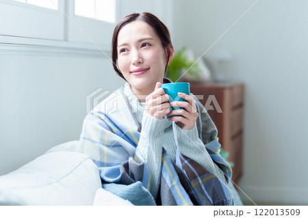 ホットドリンクを飲んで体を温める女性 ホットドリンクを飲んで体を温める女性 122013509