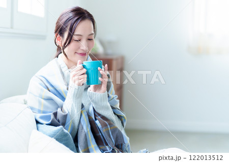 ホットドリンクを飲んで体を温める女性 ホットドリンクを飲んで体を温める女性 122013512