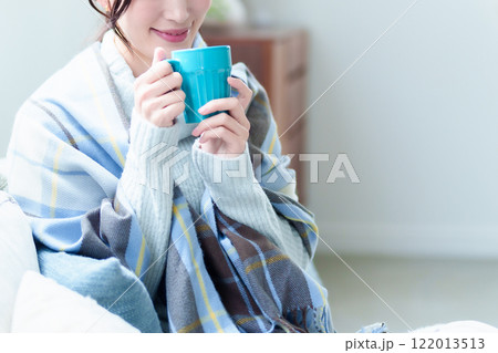 ホットドリンクを飲んで体を温める女性 ホットドリンクを飲んで体を温める女性 122013513