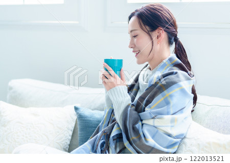 ホットドリンクを飲んで体を温める女性 122013521