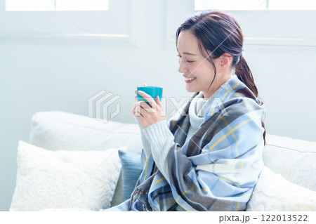 ホットドリンクを飲んで体を温める女性 122013522
