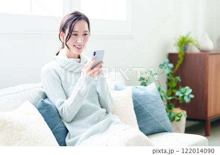 リビングでスマートフォンを使う主婦 リビングでスマートフォンを使う主婦 122014090