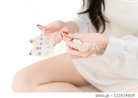 サプリメントケースを持って錠剤を掴む若い女性　パーツカット 122014889