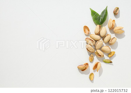 Pistachios in the shell with leaves, on a light background. Pistachios in the shell with leaves, on a light background. 122015732