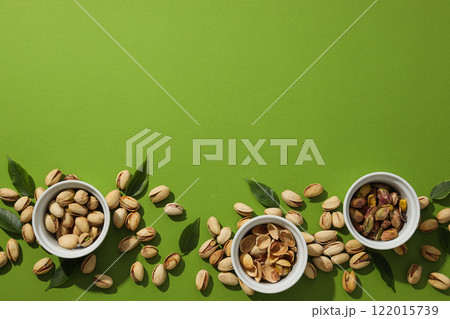 Pistachios in a plate, on a green background. 122015739