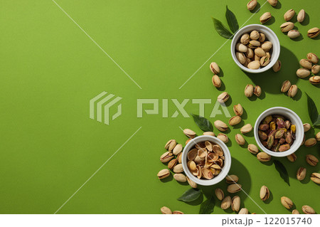 Pistachios in a plate, on a green background. 122015740