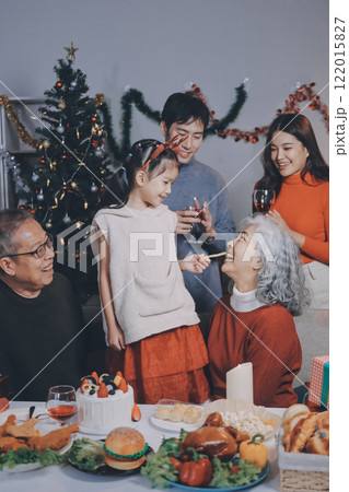 Multi-Generation Family Celebrate Christmas At Home Wearing Santa Hats And Antlers Opening Presents Multi-Generation Family Celebrate Christmas At Home Wearing Santa Hats And Antlers Opening Presents 122015827