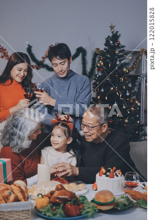 Multi-Generation Family Celebrate Christmas At Home Wearing Santa Hats And Antlers Opening Presents 122015828
