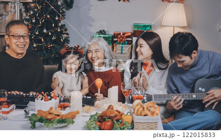 Multi-Generation Family Celebrate Christmas At Home Wearing Santa Hats And Antlers Opening Presents Multi-Generation Family Celebrate Christmas At Home Wearing Santa Hats And Antlers Opening Presents 122015833
