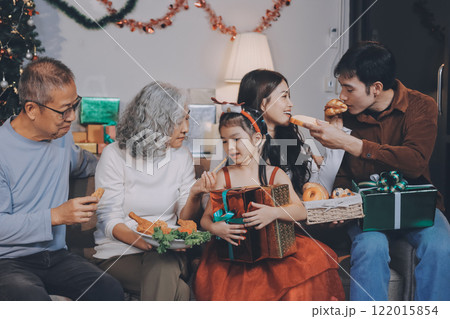 Portrait of Asian family exchanging presents during christmas at home. Attractive happy people holding gift box, celebrate holiday thanksgiving, xmas eve tradition in living room in house together. 122015854