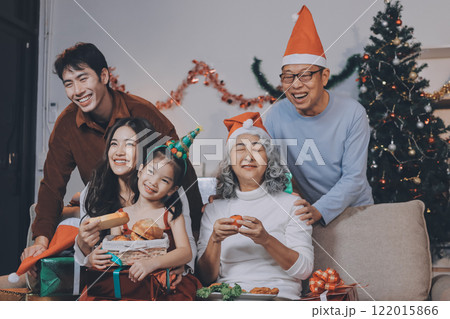 Portrait of Asian family exchanging presents during christmas at home. Attractive happy people holding gift box, celebrate holiday thanksgiving, xmas eve tradition in living room in house together. 122015866