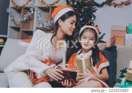 Merry Christmas and Happy Holidays. Cheerful mom and her cute daughter girl exchanging gifts. Parent and little child having fun near tree indoors. Merry Christmas and Happy Holidays. Cheerful mom and her cute daughter girl exchanging gifts. Parent and little child having fun near tree indoors. 122015897