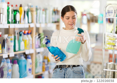 Girl housewife in household store examines package, chooses household chemical spray 122016038