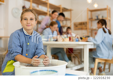 Girl working at a potter's wheel 122016230