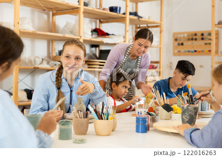 Children painting ceramics with a teacher Children painting ceramics with a teacher 122016263