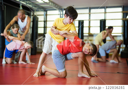 Boys and girls in gym exercising armlock move 122016281
