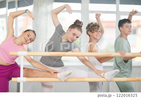 Two teenage girls practicing leg stretching exercise during ballet classes 122016325