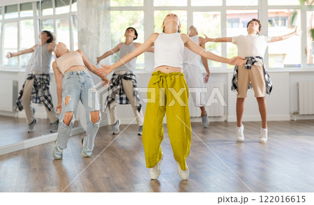 Teenage girl practicing hip hop slide moves in training hall Teenage girl practicing hip hop slide moves in training hall 122016615
