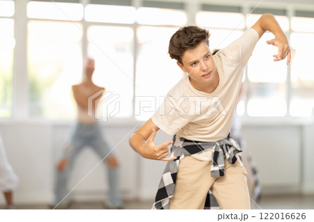 Teenage boy dancing hip-hop against background of group members Teenage boy dancing hip-hop against background of group members 122016626