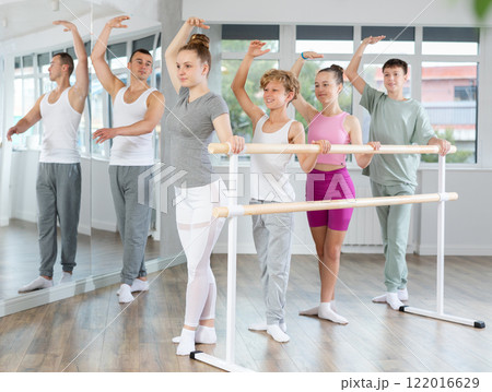 Girls and boys in ballet class perform third position under male teacher guidance. Girls and boys in ballet class perform third position under male teacher guidance. 122016629