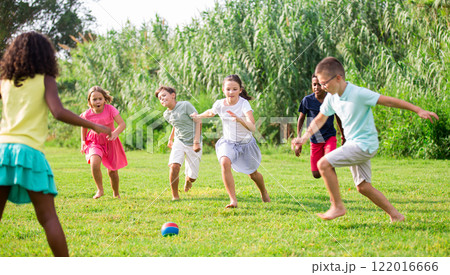 Active tweenagers playing football on green grass in summertime 122016666
