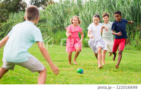 Cheerful tween friends playing with ball outdoors in summer Cheerful tween friends playing with ball outdoors in summer 122016699