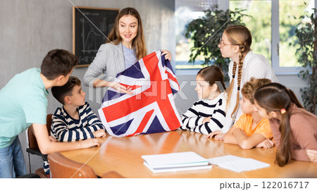 Teacher talking about country and national flag of the Great Britain at Geography lesson. Positive Schoolchildren and female teacher discussing 122016717
