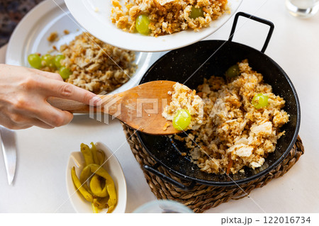 Female hands portioning Migas del pastor with grapes into plates 122016734