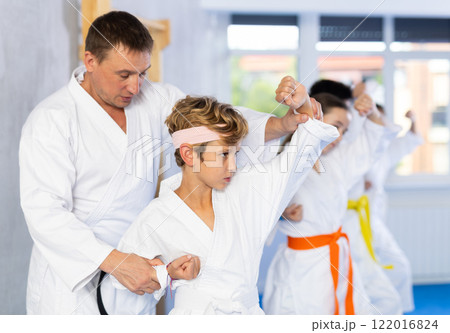 Teacher corrects pupil pose posture position of body, hands, legs during karate classes 122016824