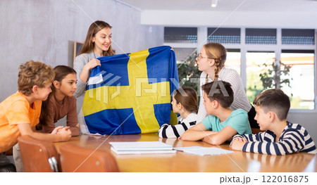 Teacher showing Sweden flag to group of schoolchildren 122016875