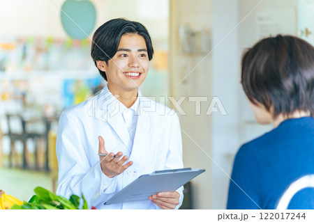 女性と会話する若い白衣の男性　医師　カウンセラー 122017244