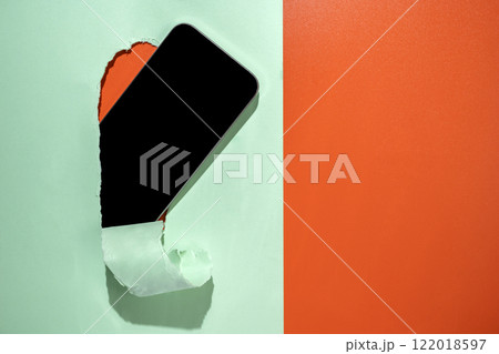 Blank mobile phone from the hole of ripped paper. Mockup or Copy space. Template. Concept of technology or communication 122018597