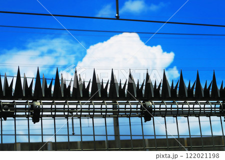 鉄道の柵上のステンレス アムレット（忍び返し）と青空の風景 122021198