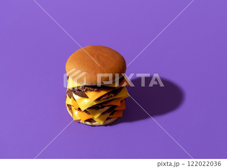Large cheeseburger with beef and cheese, isolated on a purple background. Large cheeseburger with beef and cheese, isolated on a purple background. 122022036