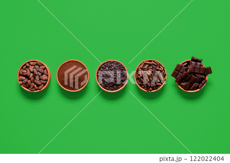Cacao and chocolate variety in bowls isolated on a green background, above view Cacao and chocolate variety in bowls isolated on a green background, above view 122022404