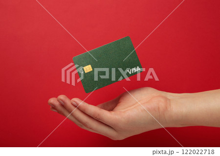 Hand with flying credit card Visa on red background. Nikolaev, Ukraine - February 14, 2022 122022718