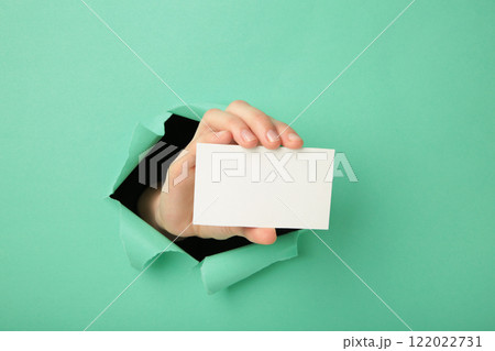 Female hand with gift box punching through the pink paper Female hand with gift box punching through the pink paper 122022731