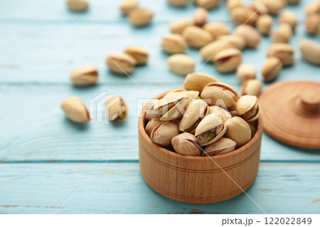 Pile of Pistachios on wooden bowl, pistachios on blue wooden background. Pile of Pistachios on wooden bowl, pistachios on blue wooden background. 122022849