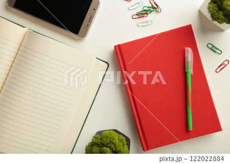Red notebook with smartphone on grey background. 122022884