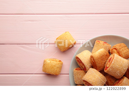 Homemade cookies, mini rolls with apricot jam in plate on pink wooden background. Vertical photo. 122022899