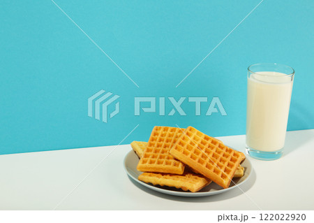 Belgian waffles on blue and white background. Belgian waffles with honey and milk. Freshly baked Belgian waffles. 122022920