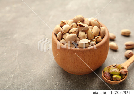 Pile of Pistachios on wooden bowl, pistachios on grey background. Pile of Pistachios on wooden bowl, pistachios on grey background. 122022921