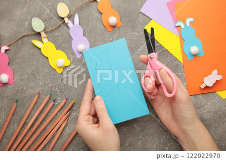 DIY and kid's creativity. How to make paper greeting cards with a bunny, cut out blanks from multi-colored paper. (Sheets of colored paper, scissors) 122022970
