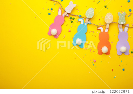 Easter bunnies handmade from colored paper on a rope with clothespins easy crafts for children on yellow background. Easter bunnies handmade from colored paper on a rope with clothespins easy crafts for children on yellow background. 122022971