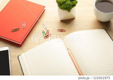 Open notebook with smartphone and cup of coffee on beige background. 122022975