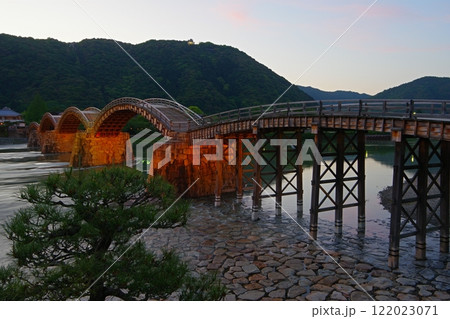 日暮れの空と岩国城を背景にライトアップの始まった錦帯橋の夕景　Ver2 122023071