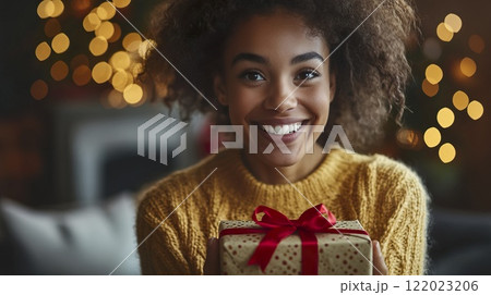 Woman holding a gift box with a red bow in a bright indoor setting 122023206