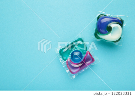 Laundry capsule detergent pods for washing clothes on blue background. Laundry capsule detergent pods for washing clothes on blue background. 122023331