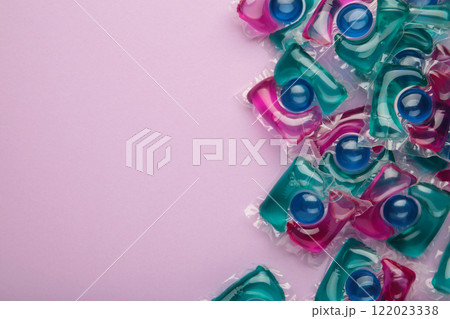 Laundry capsule detergent pods for washing clothes on purple background. 122023338
